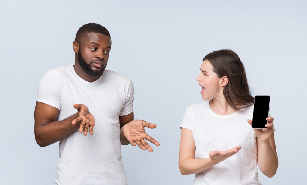 Angry girlfriend asking explanation from her unfaithful boyfriend, demonstrating his smartphone