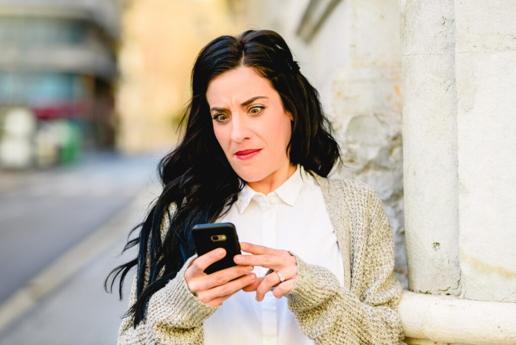 Brunette woman consulting her mobile phone and receiving bad news.