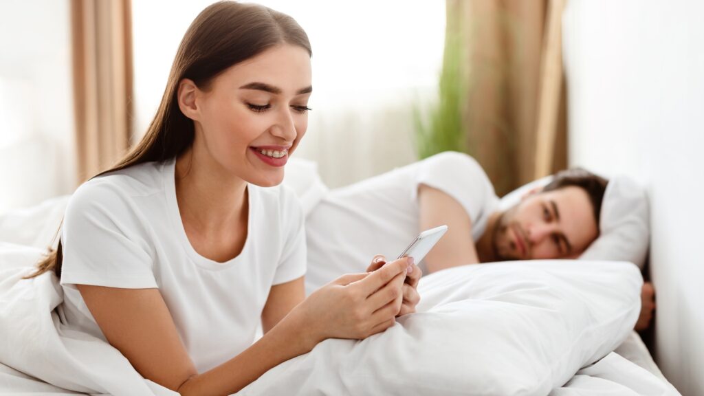 Cheating Wife Texting On Phone While Husband Sleeping In Bedroom