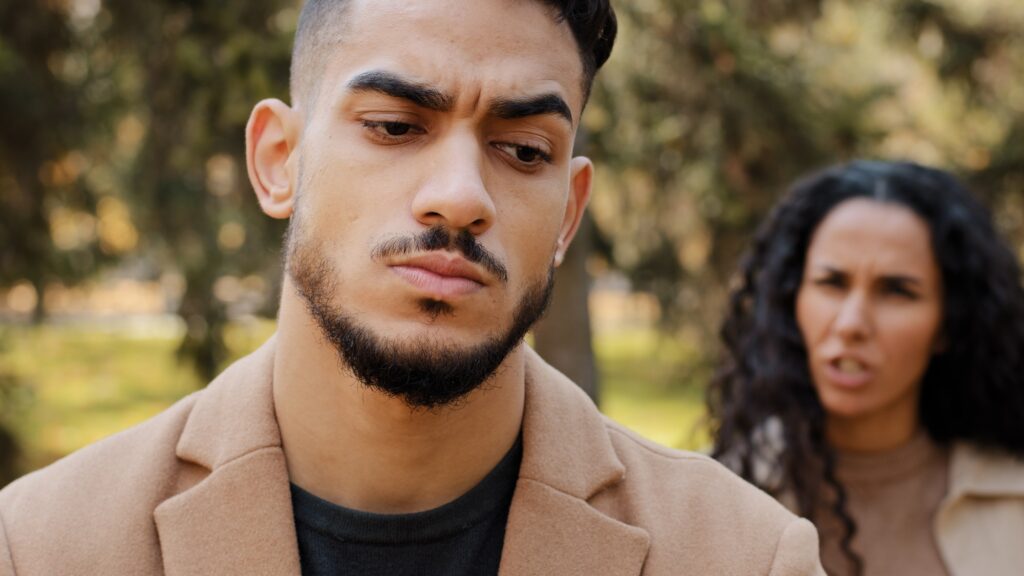 Emotional quarrel of hispanic couple outdoors angry girlfriend in background yelling and scolding