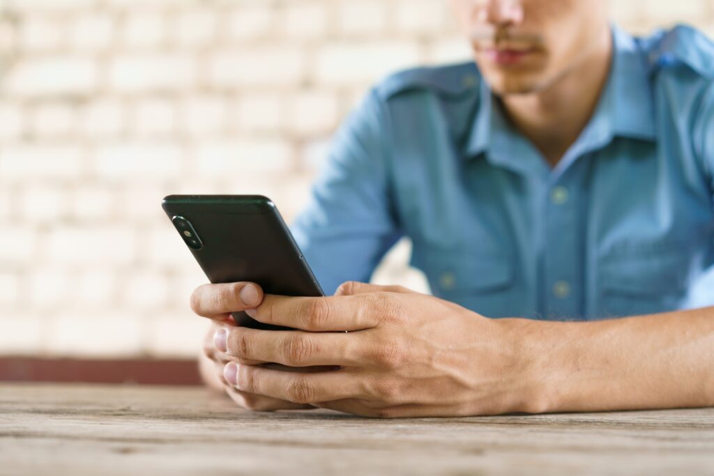 Freelance guy texting on phone. Caucasian young man in blue