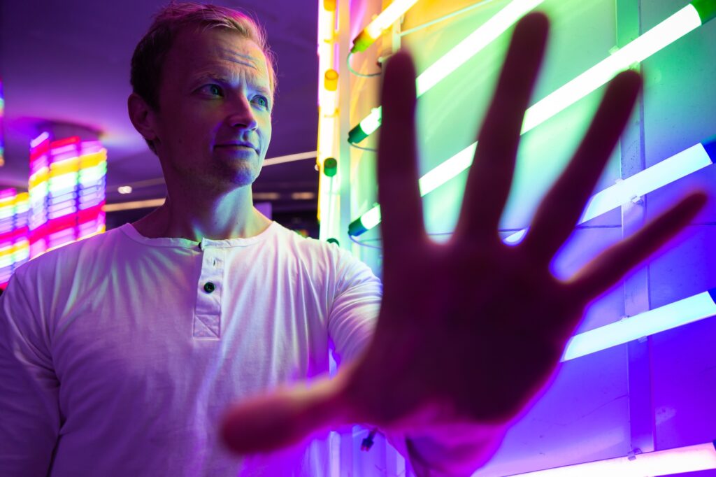 Man making a stop gesture while looking away in front of neon lights