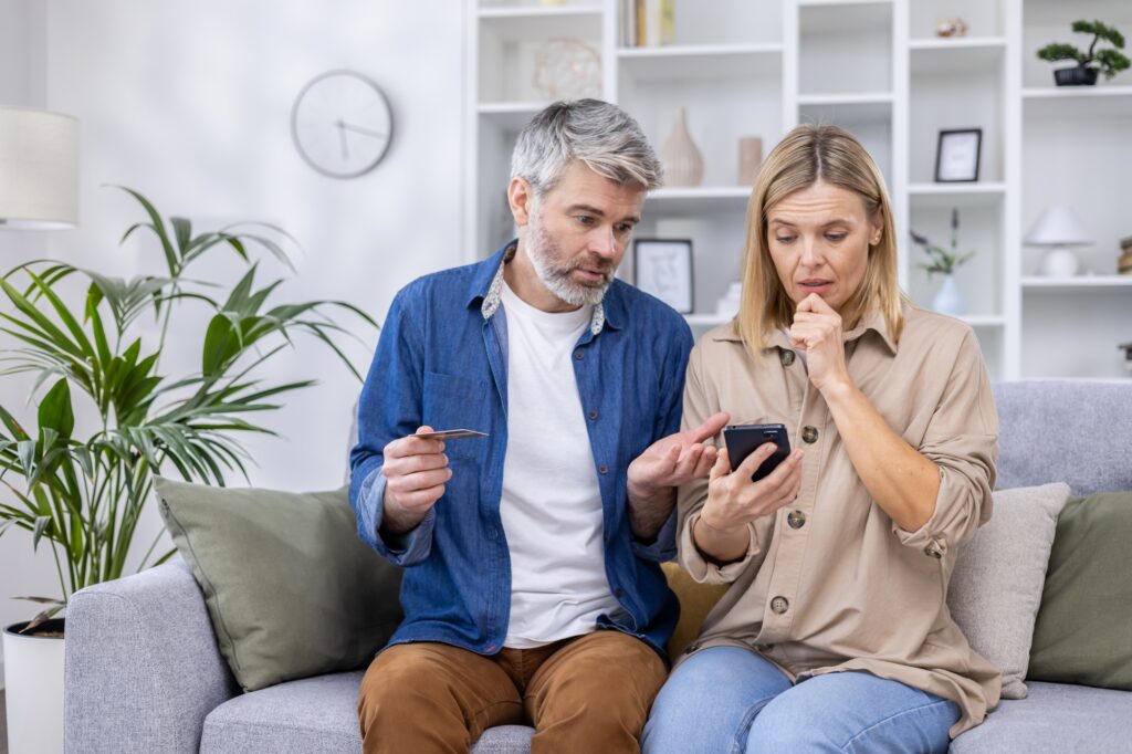 Upset and cheated couple, man and woman disappointed sitting together on couch in living room