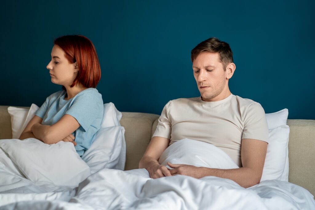 Wife husband having hard conversation sitting in bed at home trying to save relationship.