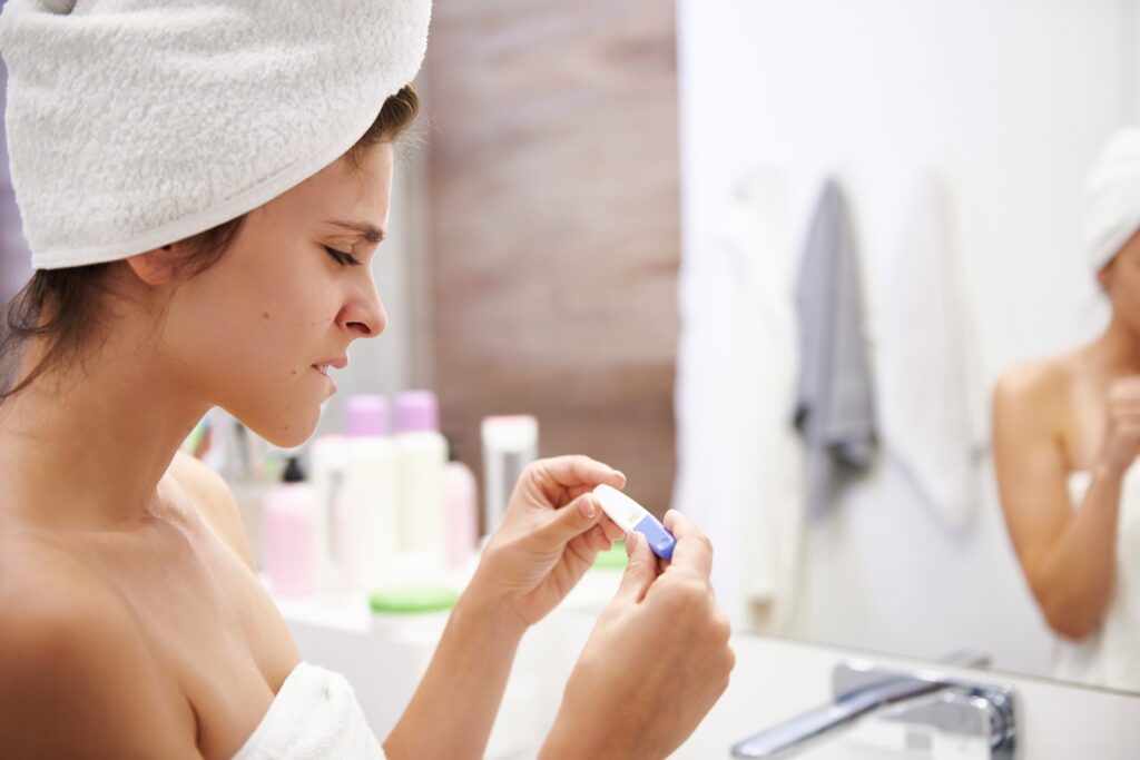 Young woman in bathroom worrying over pregnancy test result